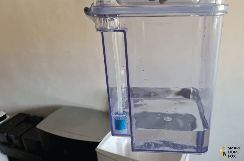 Der Frischwassertank aus der OMNI Station des ECOVACS DEEBOT T20 nach der Säuberung einer 80 m² Wohnung wird in den Händen gehalten.
